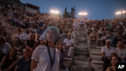 Una acomodadora con una pantalla facial se ve delante del público en el anfiteatro Odeón de Herodes Ático, en Atenas, Grecia, el 15 de julio de 2020, cuando se reiniciaron las presentaciones..
