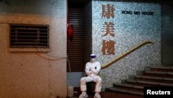 Un hombre con traje sanitario protector espera para evacuar residente de un edificio de viviendas públicas en Hong Kong, por varios casos de coronavirus. Febrero 11 de 2020. Reuters.
