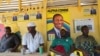 People sit inside a local restaurant displaying posters for Guinea’s incumbent President Alpha Conde, in Conakry, Guinea, Oct. 17, 2015.