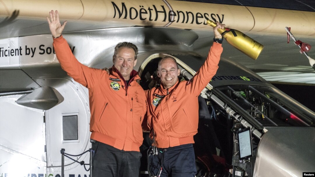 Pilot Bertrand Piccard (kanan) dan pilot cadangan Andre Broschberg,keduanya dari Swiss, melambaikan tangan mereka di depan pesawat Solar Impulse 2 (Si2), sesaat setelah mendarat di bandara internasional Tulsa, Oklahoma (12/5).
