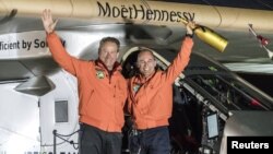 Pilot Bertrand Piccard (kanan) dan pilot cadangan Andre Broschberg,keduanya dari Swiss, melambaikan tangan mereka di depan pesawat Solar Impulse 2 (Si2), sesaat setelah mendarat di bandara internasional Tulsa, Oklahoma (12/5).