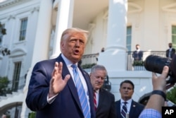 FILE - President Donald Trump, accompanied by White House Chief of Staff Mark Meadows, second from left, speaks with reporters on the South Lawn of the White House, in Washington, July 29, 2020.