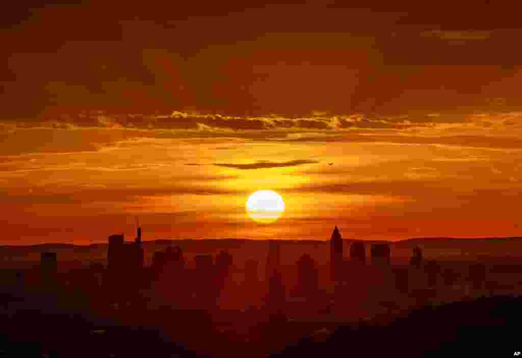 The sun rises behind buildings of the banking district in Frankfurt, Germany.