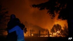 Dua perempuan saling berpelukan saat menyaksikan rumah-rumah kediaman warga di Santa Rosa, California, tengah dilalap api, Senin, 9 Oktober 2017. (AP Photo / Jeff Chiu)