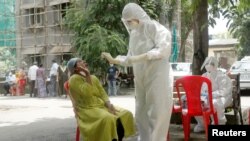 မွမ်ဘိုင်းမြို့မှာ ကိုရိုနာဗိုင်းရပ်စ် ကူးစက်မှုရှိမရှိ အမျိုးသမီးတဦးထံက swab နမူနာ ယူဖို့ ပြင်ဆင်နေတဲ့ ကျန်းမာရေးဝန်ထမ်း။ (ဇွန် ၂၉၊ ၂၀၂၀)