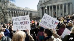 People hold anti-deportation signs during a rally, March 9, 2017, in New York. 