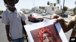 A Libyan rebel fighter shows a manipulated photograph of Moammar Gadhafi at a checkpoint in Tripoli August 29, 2011.