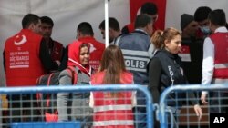 A Turkish police officer speaks with a migrant after a vessel transporting migrants from Greek island Chios docked in Dikili port, Turkey, April 4, 2016.