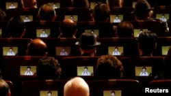 People watch South Korean President Park Geun-hye's speech on small screens fitted in their seats during a ceremony celebrating the 96th anniversary of the Independence Movement Day in Seoul, March 1, 2015.