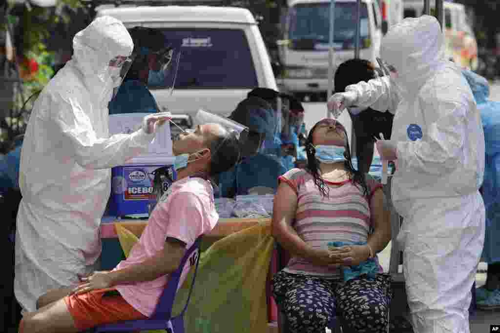 Health workers conduct a COVID-19 swab test on residents at a village in Quezon City, Philippines.