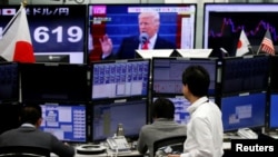 Employees of a foreign exchange trading company work near monitors showing President Donald Trump and the Japanese yen's exchange rate in Tokyo, January 23, 2017.