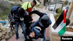 A wounded Palestinian photojournalist is evacuated during an anti-Israel protest against the U.S. President Donald Trump's Middle East peace plan, in Hebron in the Israeli-occupied West Bank.