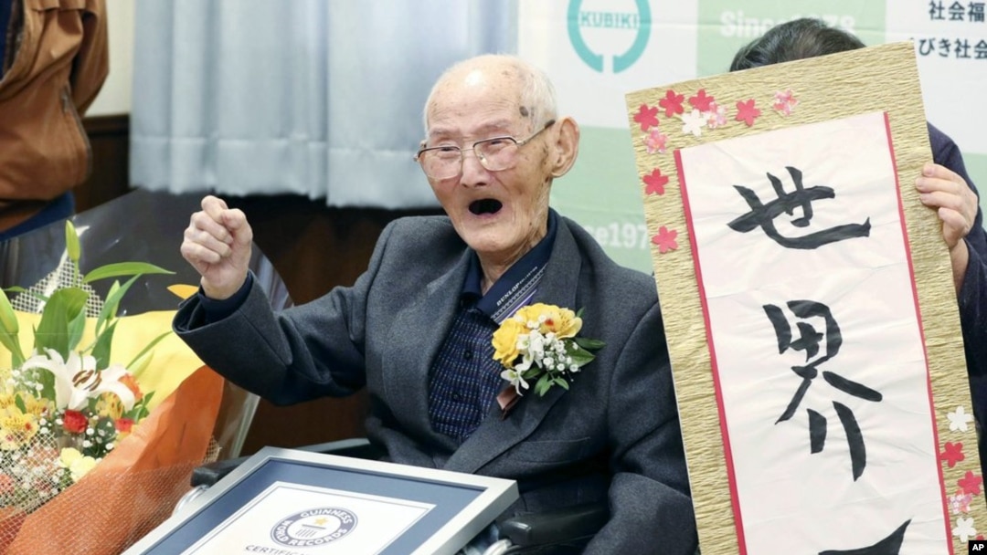 Chitetsu Watanabe (112), berpose di sebelah kaligrafi yang ia tulis setelah dianugerahi sebagai lelaki tertua di dunia oleh Guinness World Records, di Joetsu, prefektur Niigata, Jepang utara Rabu, 12 Februari 2020. (Kyodo News via AP)