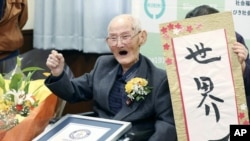 Chitetsu Watanabe (112), berpose di sebelah kaligrafi yang ia tulis setelah dianugerahi sebagai lelaki tertua di dunia oleh Guinness World Records, di Joetsu, prefektur Niigata, Jepang utara Rabu, 12 Februari 2020. (Kyodo News via AP)