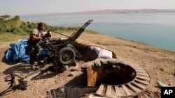 Un combatiente peshmerga kurdo prepara un cañón en una trinchera cerca de la presa de Mosul, retomada por los kurdos.