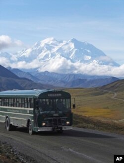 A shuttle bus carrying tourists makes its way along the park road with North America's tallest peak, Denali, in the background, in Denali National Park and Preserve, Alaska, Aug. 26, 2016.