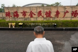 A man stands near flowers laid outside the Zhuhai People's Fitness Plaza where a man rammed his car into people exercising at the sports center, in Zhuhai in southern China's Guangdong province on Nov. 13, 2024.