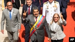 El presidente venezolano Nicolás Maduro y su esposa, Cilia Flores, saludan a su entrada al Palacio Federal Legislativo, en Caracas, este lunes, para presentar su memoria y cuenta anual. Les acompaña el presidente del parlamento, Jorge Rodríguez, a la izquierda en la fotografía.