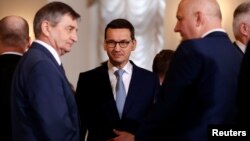 Poland's Prime Minister Mateusz Morawiecki speaks with Marek Kuchcinski (L), speaker of parliament and Joachim Brudzinski, newly sworn-in Interior Minister after a ceremony at Presidential Palace in Warsaw, Jan. 9, 2018. 