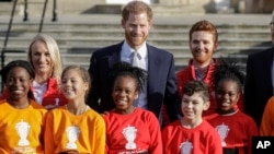 Pangeran Harry berpose dengan anak-anak dan Duta Piala Dunia Liga Rugby 2021, James Simpson (kanan) dan Jody Cunningham di taman Istana Buckingham di London, 16 Januari 2020. (Foto: AP)