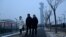 People walk along a path as the Beijing Olympic Tower is seen during a smoggy day in Beijing, Jan. 24, 2022. 