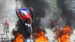 Seorang demonstran mengibarkan bendera Haiti saat protes menuntut pengunduran diri PM Ariel Henry di Port-au-Prince, Haiti, Jumat, 1 Maret 2024. Dewan penguasa transisi Haiti dijadwalkan akan dilantik padaKamis (25/4). (Foto: AP)