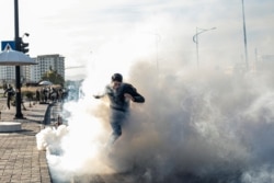 A protester runs through teargas as Kurdish security forces approach during anti-government demonstrations in the Iraqi Kurdistan city, Sulaymaniyah on Dec. 11, 2020. (Rebaz Majeed/VOA)