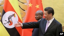 FILE - Ugandan President Yoweri Museveni, left, is shown the way by Chinese President Xi Jinping as they attend a signing ceremony in the Great Hall of the People in Beijing, China, March 31, 2015.