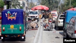 Para petugas keamanan setempat memeriksa lokasi serangan bom di Peshawar, Pakistan (29/3).