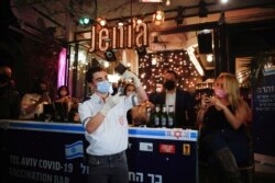 FILE - A medical worker prepares to administer a vaccination against COVID-19 as part of a Tel Aviv municipality initiative offering a free drink at a bar to residents getting the shot, in Tel Aviv, Israel, Feb. 18, 2021.