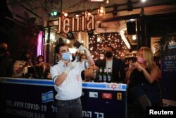 FILE - A medical worker prepares to administer a vaccination against COVID-19 as part of a Tel Aviv municipality initiative offering a free drink at a bar to residents getting the shot, in Tel Aviv, Israel, Feb. 18, 2021.