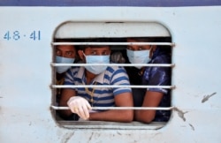 FILE - Migrant workers, who were stranded in the western state of Rajasthan due to a coronavirus lockdown, look out from the window of a train upon their arrival in their home state of eastern West Bengal, India, May 5, 2020.