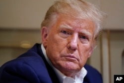 FILE - Former President Donald Trump speaks with reporters while in flight on his plane after a campaign rally at Waco Regional Airport, in Waco, Texas, March 25, 2023