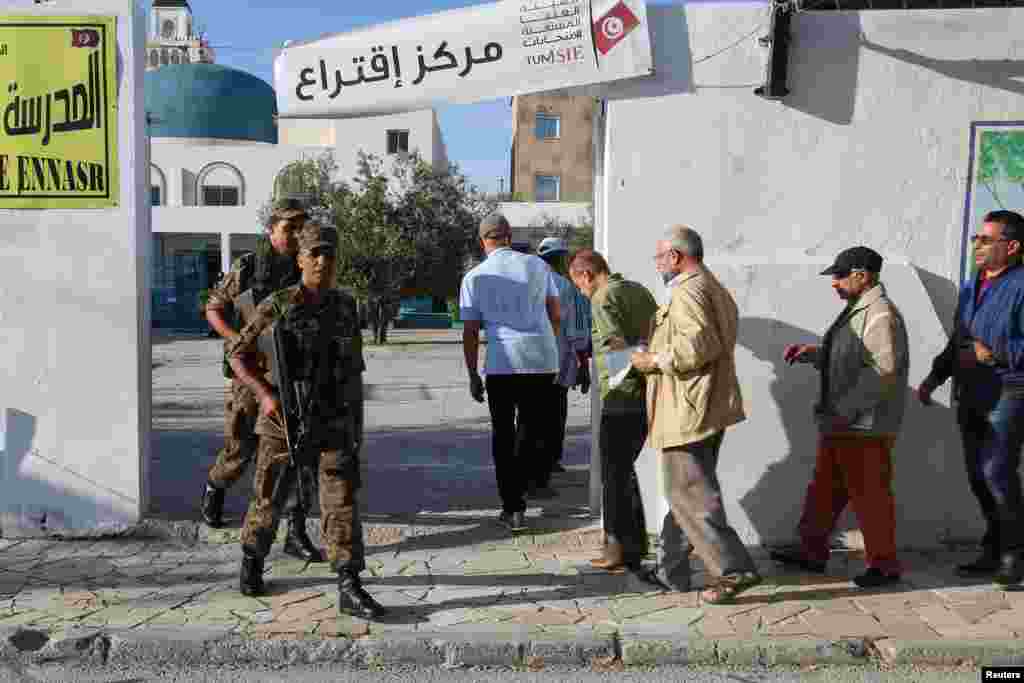 Wanajeshi washika zamu nje ya kituo cha kupiga kura Tunis watu wakingia
