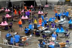 FILE - Maricopa County ballots cast in the 2020 general election are examined and recounted by contractors working for Florida-based company Cyber Ninjas at Veterans Memorial Coliseum in Phoenix, May 6, 2021.