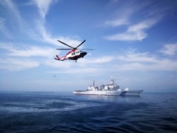 FILE - This photo from the Malaysian Maritime Enforcement Agency shows the Japan Coast Guard ship Tsugaru and helicopters of the Malaysian Maritime Enforcement Agency during a joint exercise off Kuantan, Malaysia, Jan. 29, 2018.