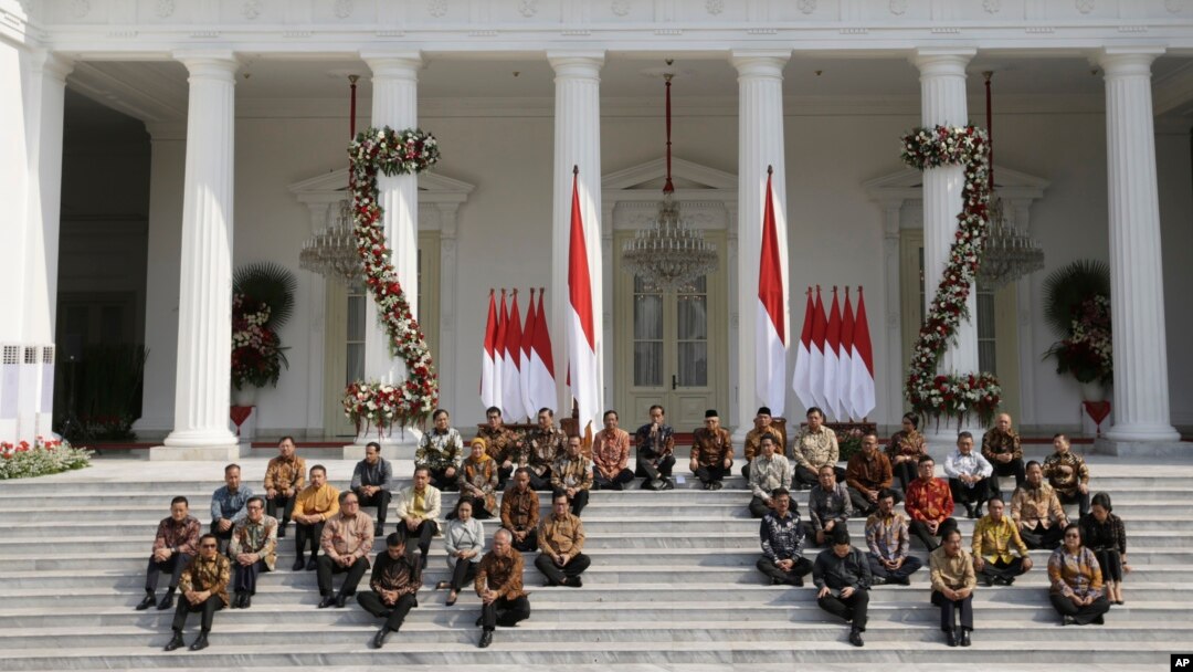 Presiden Joko Widodo (baris atas ke-5 dari kiri) dan Wakil Presiden Ma'ruf Amin (ke-6 dari kiri) bersama menteri-menteri kabinet baru duduk di tangga saat mengumumkan nama menteri-menteri baru, Rabu, 23 Oktober 2019. (Foto: AP)