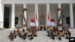 Presiden Joko Widodo (baris atas ke-5 dari kiri) dan Wakil Presiden Ma'ruf Amin (ke-6 dari kiri) bersama menteri-menteri kabinet baru duduk di tangga saat mengumumkan nama menteri-menteri baru, Rabu, 23 Oktober 2019. (Foto: AP)