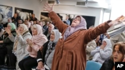 Ediba Salihovic, right, stands up and raises her hands as she reacts along with other Bosnian women upon hearing the sentence at the end of former Bosnian Serb military chief Gen. Ratko Mladic's trial, near Srebrenica, Bosnia.