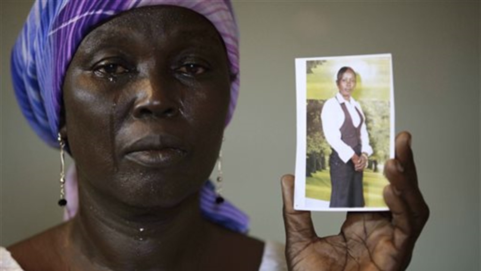 FILE - In this Monday, May 19, 2014 file photo, Martha Mark, the mother of kidnapped school girl Monica Mark cries as she displays her photo, in the family house, in Chibok, Nigeria. At least 11 parents of the more than 200 kidnapped Nigerian schoolgirls 