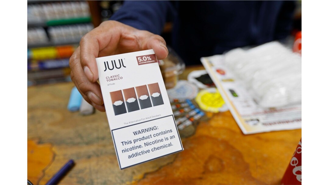 FILE - A cashier displays a packet of tobacco-flavored Juul pods at a store in San Francisco, June 17, 2019.