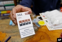 FILE - A cashier displays a packet of tobacco-flavored Juul pods at a store in San Francisco, June 17, 2019.