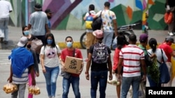 Las personas con tapabocas caminan cerca de los vendedores ambulantes en Petare, Caracas. Abril 20, 2020.