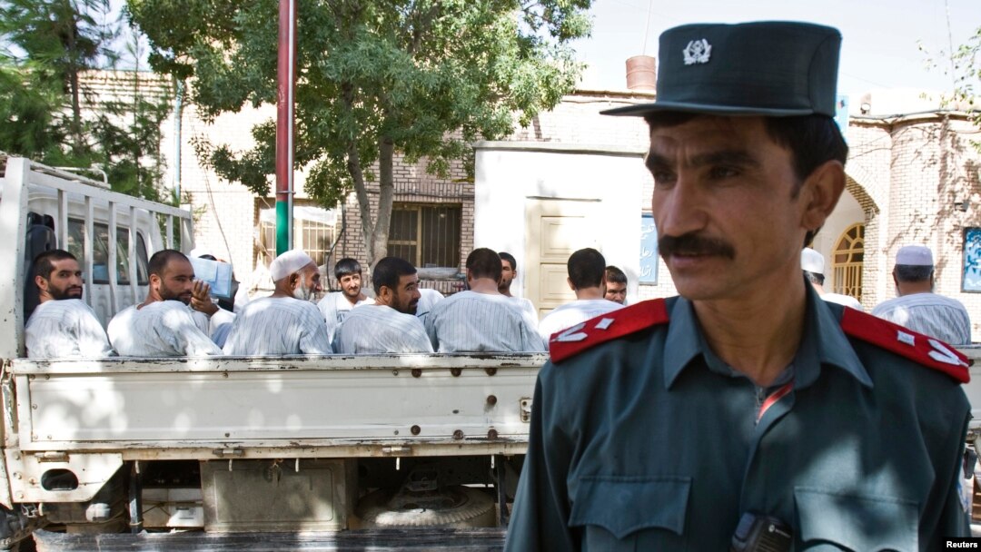 An Afghan police officer stands guard in front of a truck carrying Afghan prisoners on their way to court in Herat, western Afghanistan, August 16, 2009.