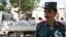 An Afghan police officer stands guard in front of a truck carrying Afghan prisoners on their way to court in Herat, western Afghanistan, August 16, 2009.
