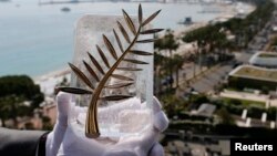 A Chopard representative displays the Palme d'Or, the highest prize awarded to competing films, during an interview before the start of the Festival, Cannes, France, May 7, 2018. 