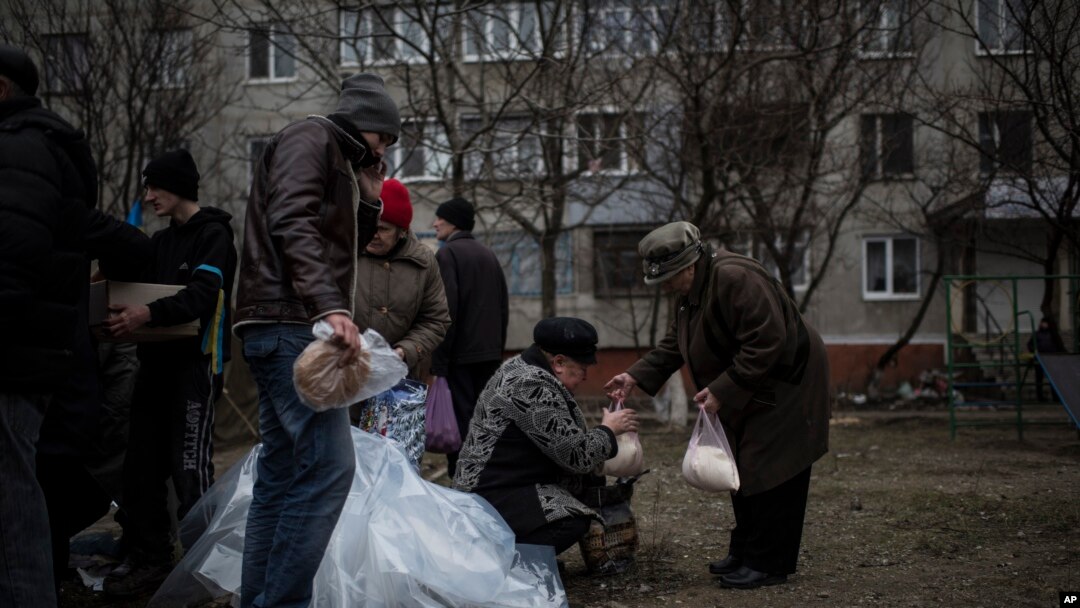 Warga lokal menerima bantuan kemanusiaan menyusul penembakan di distrik Vostochniy di Mariupol, Ukraina timur (26/1). (AP/Evgeniy Maloletka)