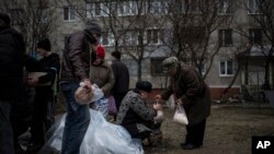 Warga lokal menerima bantuan kemanusiaan menyusul penembakan di distrik Vostochniy di Mariupol, Ukraina timur (26/1). (AP/Evgeniy Maloletka)