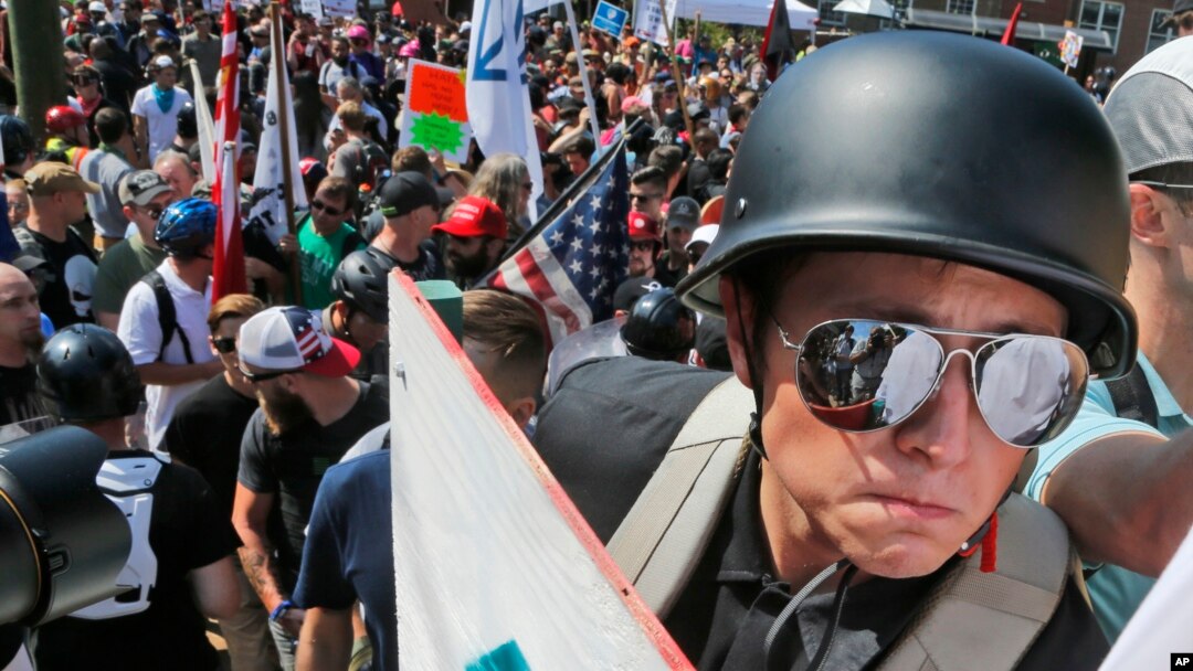 A white nationalist demonstrator with a helmet and shield walks into Lee Park in Charlottesville, Va., Aug. 12, 2017. Hundreds of people chanted, threw punches, hurled water bottles and unleashed chemical sprays on each other Saturday after violence erupted at a white nationalist rally in Virginia. 
