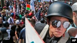 A white nationalist demonstrator with a helmet and shield walks into Lee Park in Charlottesville, Va., Aug. 12, 2017. Hundreds of people chanted, threw punches, hurled water bottles and unleashed chemical sprays on each other Saturday after violence erupted at a white nationalist rally in Virginia. 